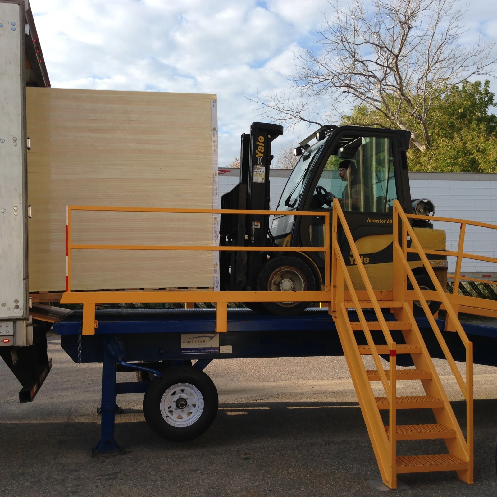 Adapt A Ramp mobile loading ramps showing a Forklift driving on M35 Ramp. The ramp also features a set of stairs.